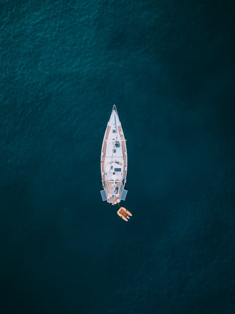 A top-down drone view of a sailboat in serene waters off the coast of Spain.